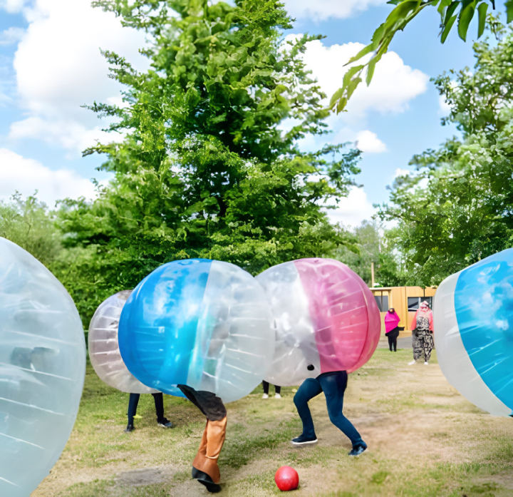 Des joueurs dans des bulles gonflables transparentes se bousculent autour d'un ballon, sur l'herbe