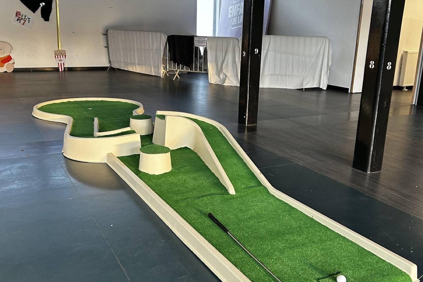 Des pistes de minigolf en gazon synthétique posées dans une salle.